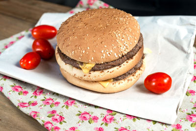 High angle view of hamburger with tomatoes on paper over table