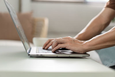 Midsection of woman using laptop on table