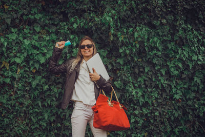 Portrait of young woman standing against plants