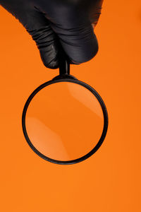 Close-up of person holding camera against orange background