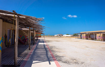 Empty road by street against blue sky