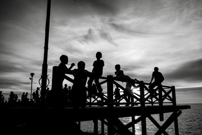 Silhouette people standing by sea against sky