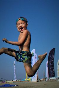 Low angle view of happy boy against blue sky