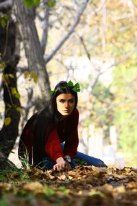 Portrait of young woman standing against trees in forest