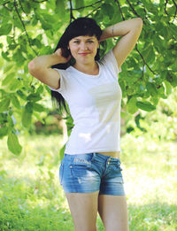 Portrait of smiling young woman standing on tree