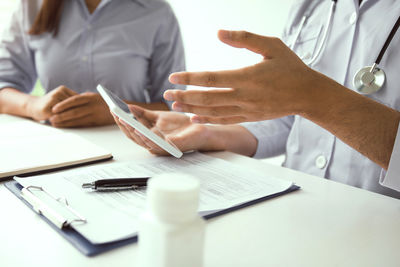 Midsection of doctor and nurse working on table