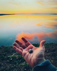 Midsection of person holding umbrella against sky during sunset