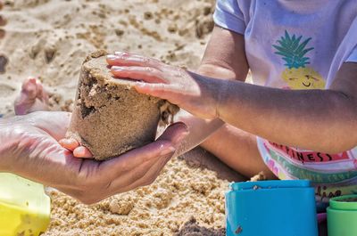Midsection of woman holding hands on sand at beach