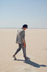 Full length of man walking on beach against sky