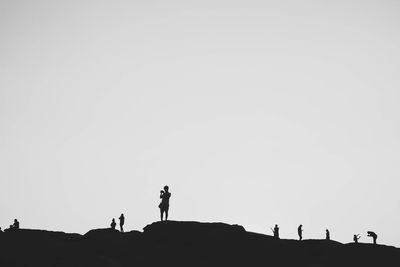 Silhouette people standing on land against clear sky