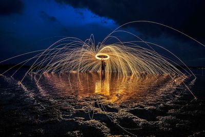 Man with wire wool on shore against sky