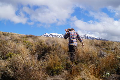 Rear view of woman standing on field against sky