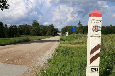 Road sign against cloudy sky