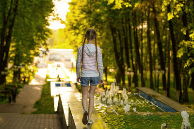 Rear view of woman walking on footpath amidst trees