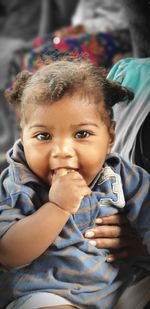 Close-up portrait of cute baby girl with finger in mouth