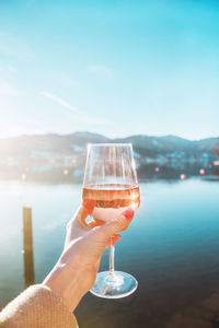 Female hand with glass of rose wine. cozy pier on the coast of lake tegernsee. mountains in bavaria