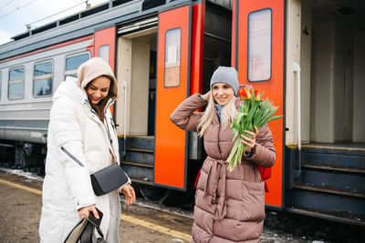 Joyful girls with flowers on the platform of the station
