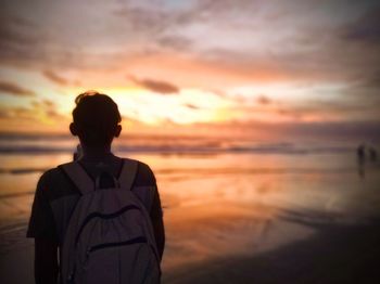 Rear view of man looking at sea during sunset