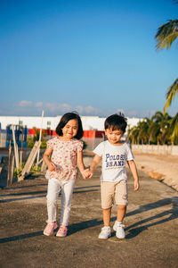 Full length of siblings and woman against sky