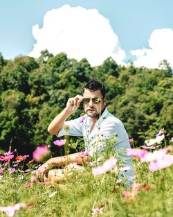 Full length of young man and flowers on field