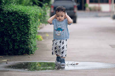 A 2-year-old asian boy walks on wet ground.