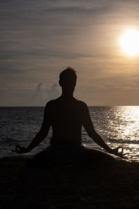 Silhouette man on beach against sky during sunset