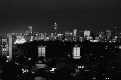 Illuminated cityscape against clear sky at night