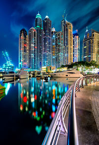 Reflection of illuminated buildings in river against sky at night