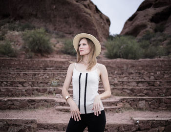Portrait of beautiful young woman standing against brick wall