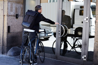 Rear view of man cycling on bicycle in city