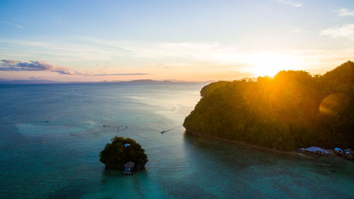 Scenic view of island amidst sea against sky during sunset