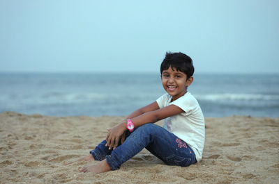 Portrait of smiling young woman sitting on beach