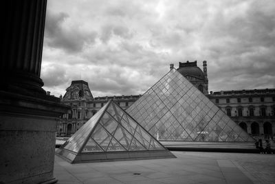 Louvre pyramid against cloudy sky