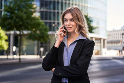 Businesswoman talking on mobile phone while standing in city
