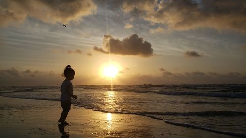 Silhouette man on beach against sky during sunset