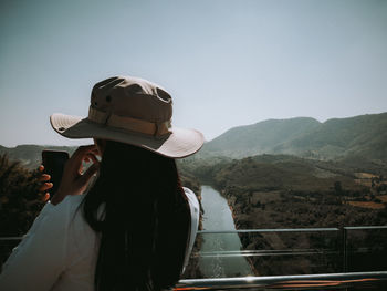 Rear view of woman standing on railing against mountain