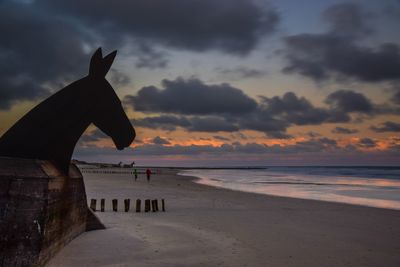 Silhouette person on beach against sky during sunset