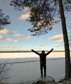 Full length rear view of man standing on shore against sky