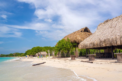 Huts at sandy beach against sky