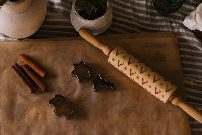 Ginger cookie molds, rolling pin and cinnamon sticks on a sheet of parchment on the table