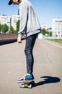 Girl skateboarding on road against sky