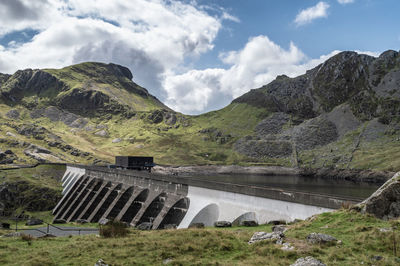 Scenic view of dam and mountains against sky