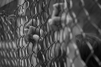 Close-up of hands on chainlink fence