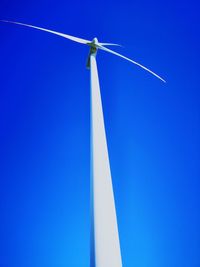 Low angle view of wind turbine against blue sky