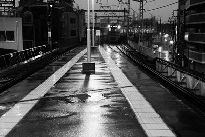 Illuminated wet railroad station platform at dusk