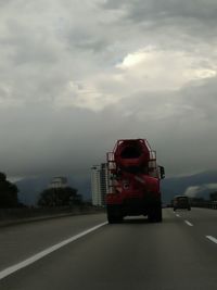 Traffic on road against cloudy sky