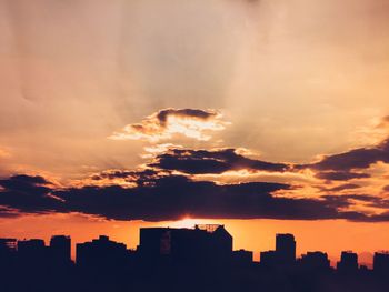 Silhouette buildings against orange sky during sunset