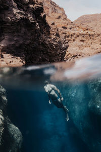 Man swimming in sea by rocks