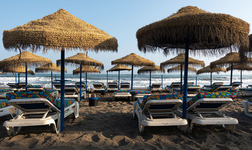 Lounge chairs and parasols on beach against sky