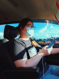 Portrait of young woman using mobile phone while sitting in car